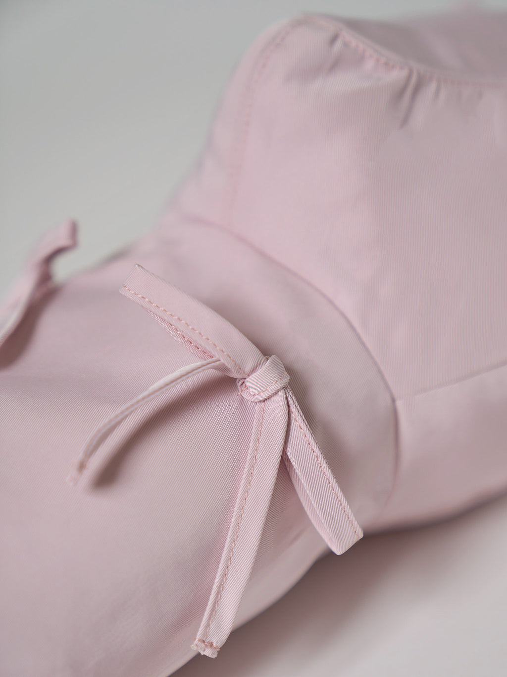 A high-performance golf driver headcover made from smooth, satin-textured nylon fabric with two playful pink ribbons sewn onto the front.