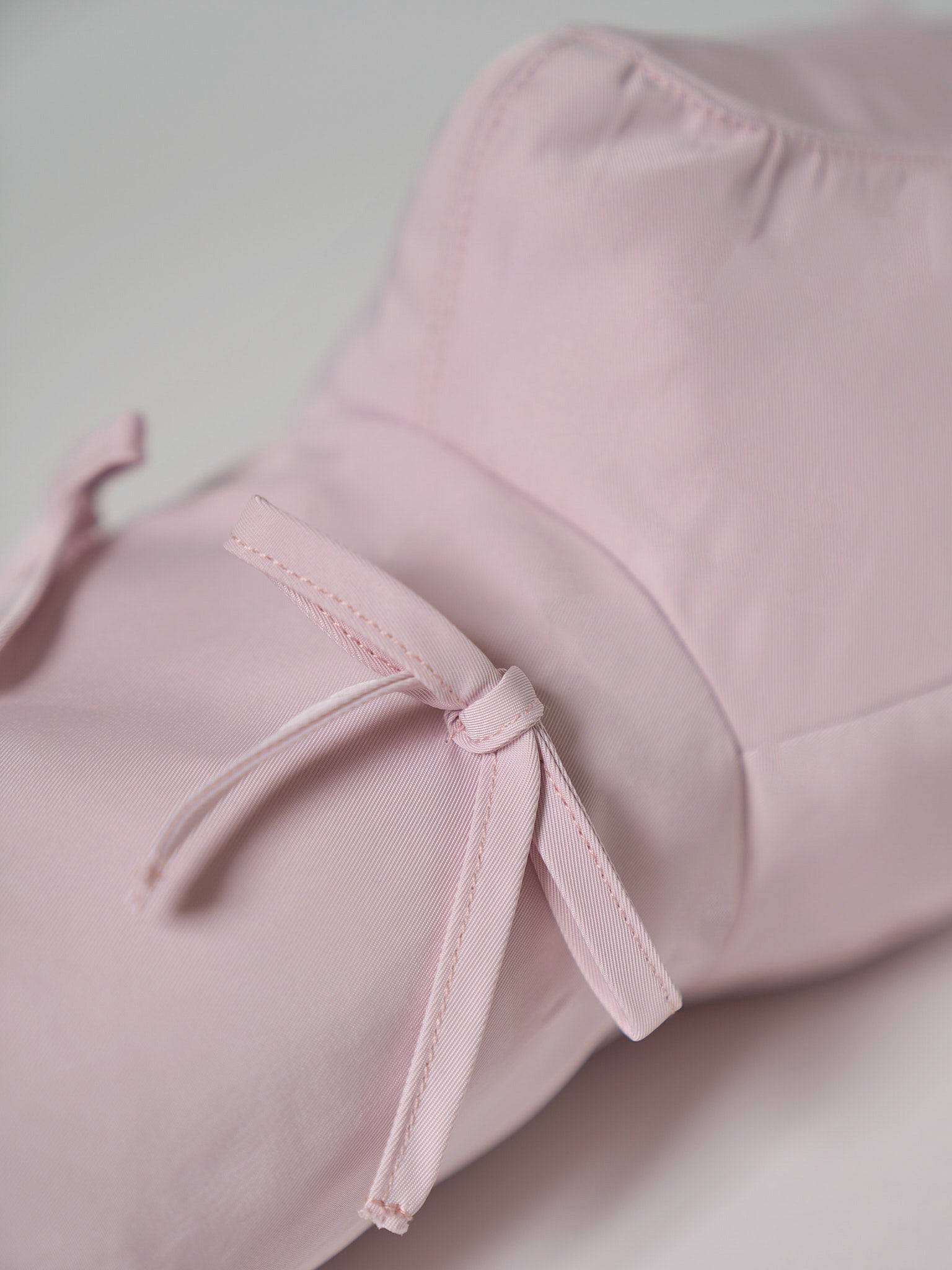 A high-performance golf driver headcover made from smooth, satin-textured nylon fabric with two playful pink ribbons sewn onto the front.
